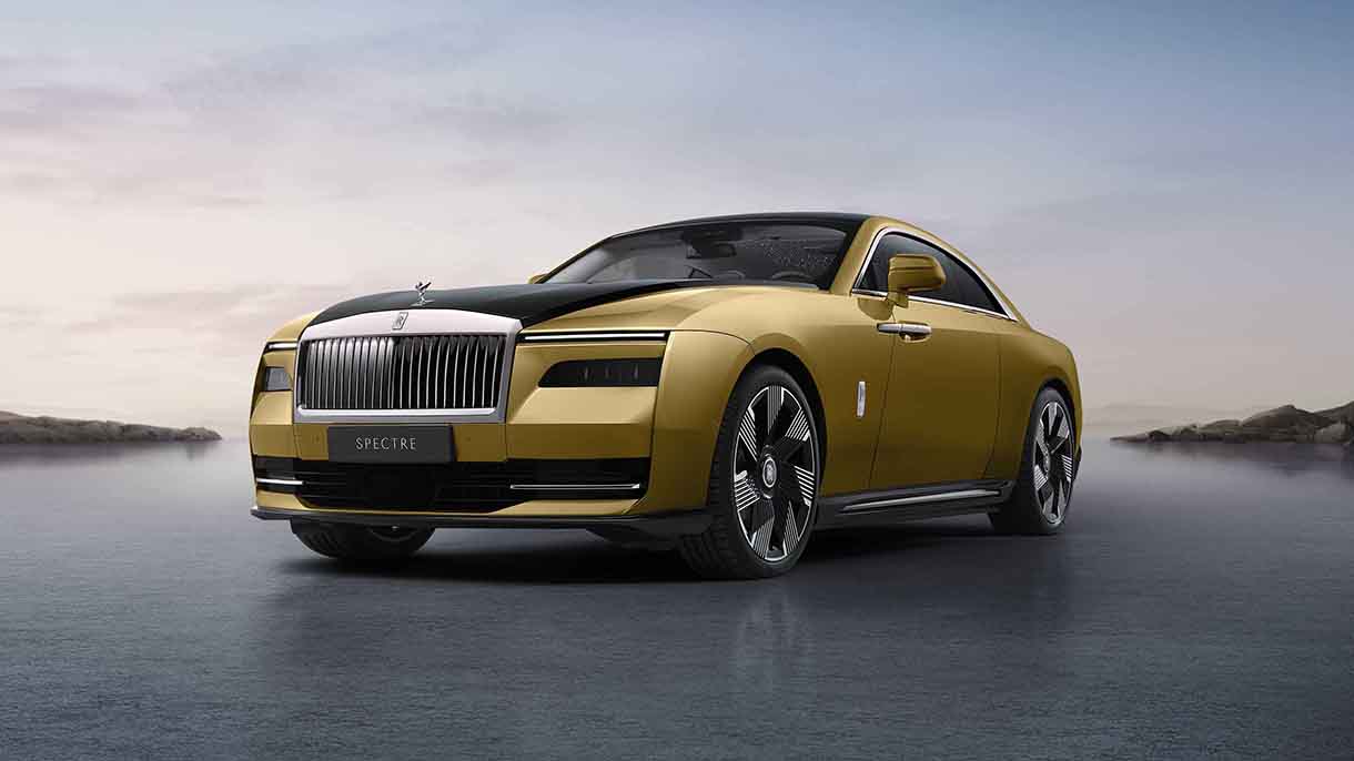 Front and side view of gold 2023 Rolls-Royce Spectre Electric Vehicle with scenic background